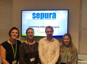 3 females and a male in front of a projector smiling at the camera