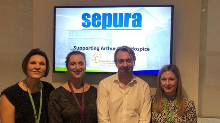 3 females and a male in front of a projector smiling at the camera