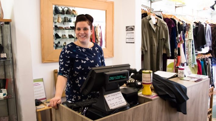Female smiling behind the till inside the Great Shelford Charity Shop