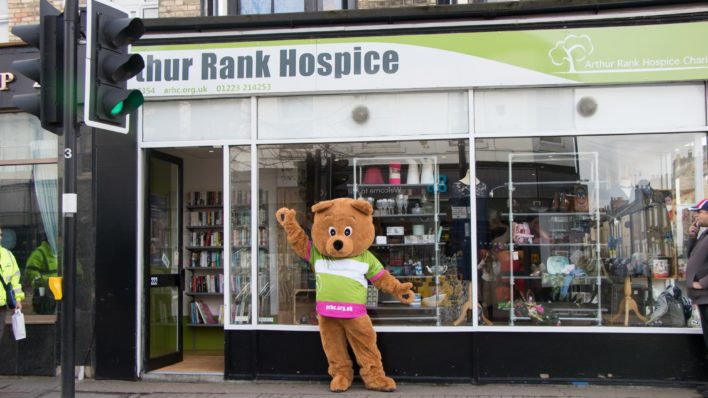Lifesized Arthur Bear mascot waving outside charity shop
