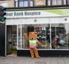 Lifesized Arthur Bear mascot waving outside charity shop