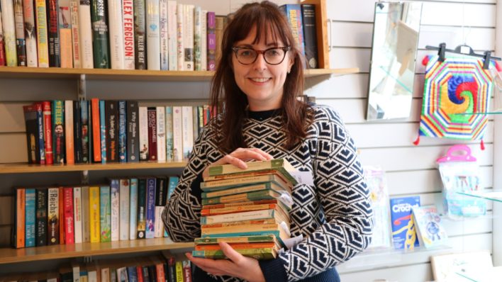 Lady holding books in our charity shop