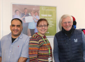 2 males and a female in a shop smiling at the camera