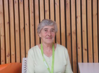 Female sitting in front of a wooden wall.