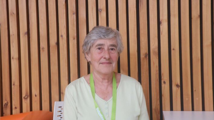 Female sitting in front of a wooden wall.