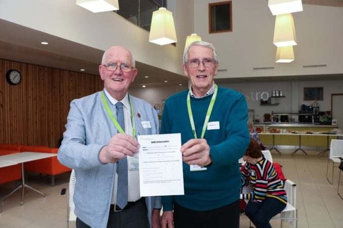 Two Ambassadors at recruitment evening, holding a poster