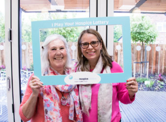 Two ladies in a 'I play the hospice lottery' photo frame