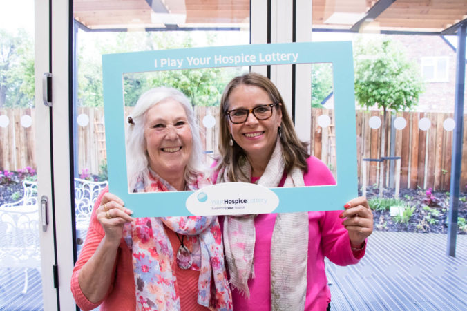 Two ladies in a 'I play the hospice lottery' photo frame