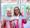 Two ladies in a 'I play the hospice lottery' photo frame