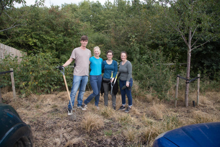1 male and 3 females standing outside in the garden with a spade