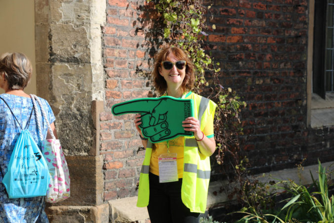 a female holding a giant pointing hand smiling at the camera