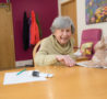 A patient in Living Well Services, laughing as she enjoys a paintint session