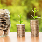 Green sprouts at the top of a stack of £ pound coins