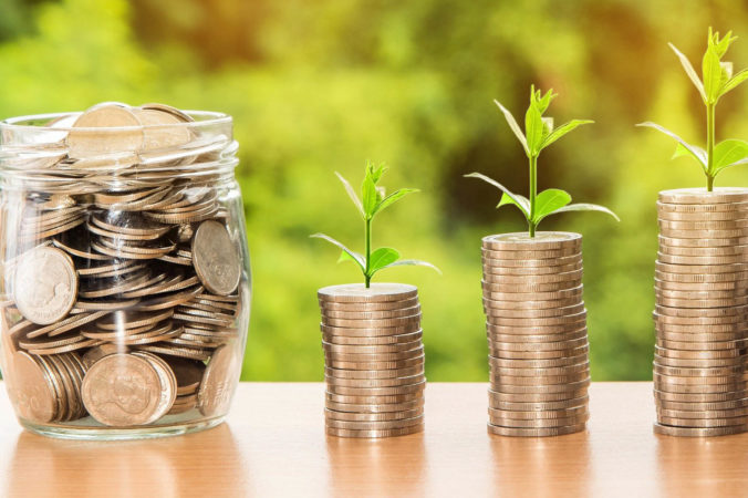 Green sprouts at the top of a stack of £ pound coins