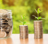Green sprouts at the top of a stack of £ pound coins