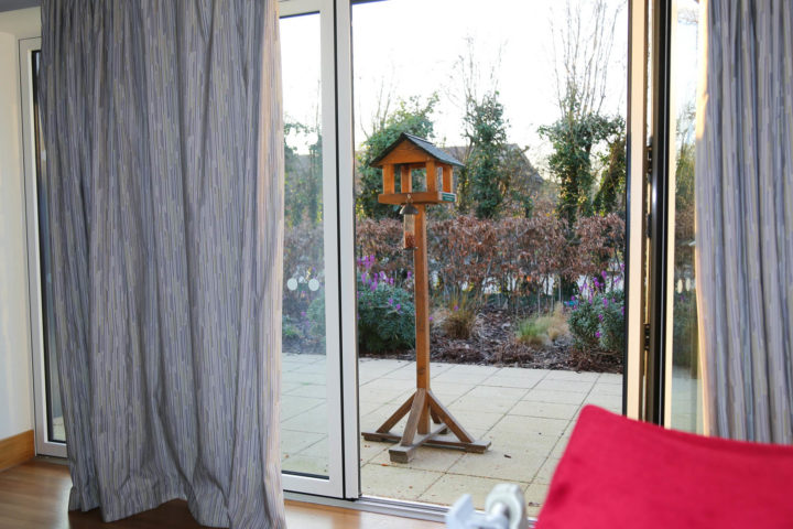 View from Inpatient Unit bedroom to bird table on patio, with flowers behind