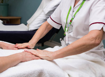 Patient's hands on towel as Therapist delivering hand massage
