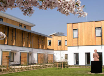 White building with half wood cladding and grass