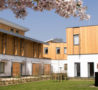 White building with half wood cladding and grass