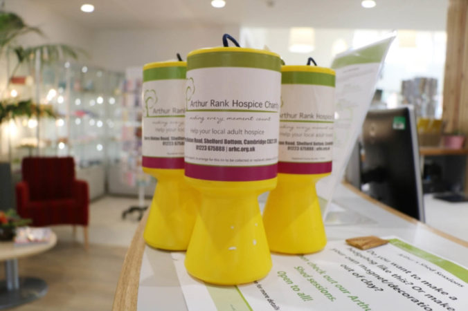 Three bright yellow collection tins with Arthur Rank Hospice Charity labels