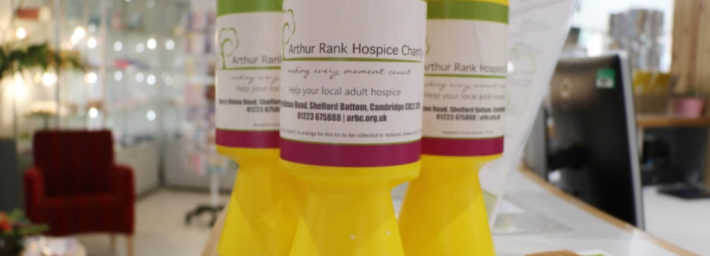 Three bright yellow collection tins with Arthur Rank Hospice Charity labels