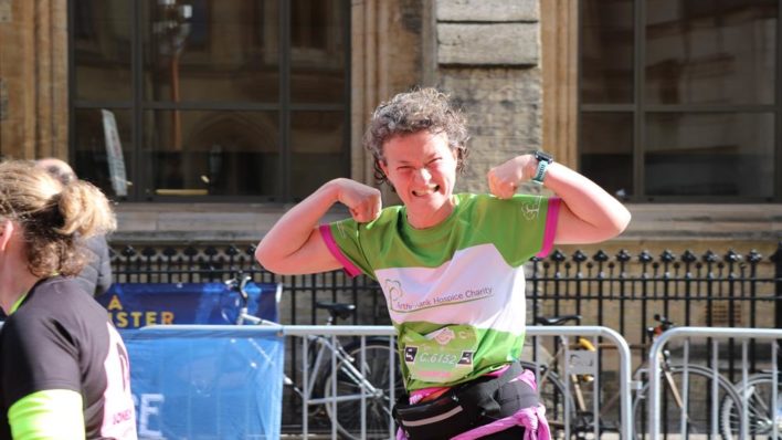 Female in green running vest smiling and arms up