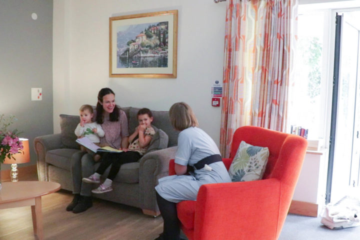 Mother with children on sofa talking to nurse