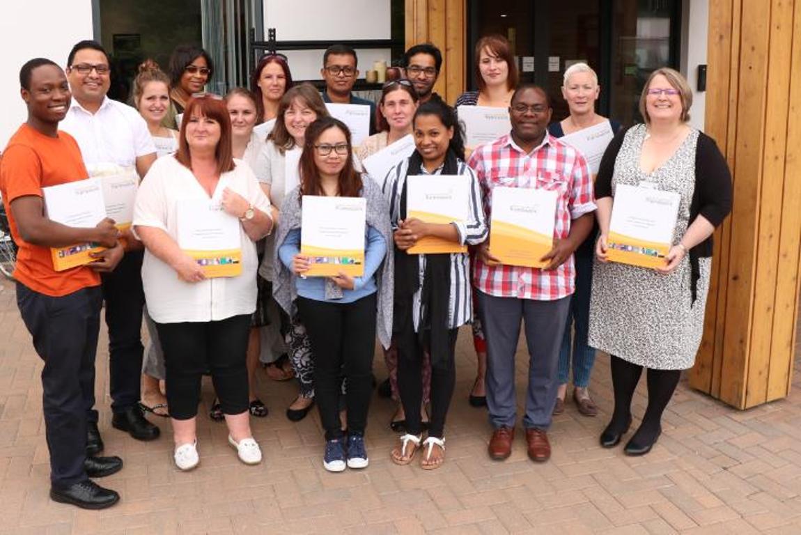 Group of care home staff receiving certificates, outside the Hospice's front entrance