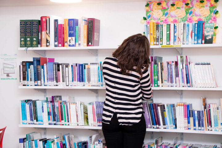 Colleague peruses book shelves of Hospice's Library