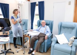 Female nurse standing with equipment and male patient sitting on a chair