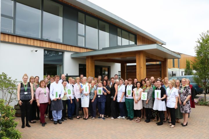 Colleagues holding JOIN US letters, at Hospice entrance