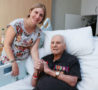War veteran with medals holds granddaughter's hand in bedroom on Inpatient Unit
