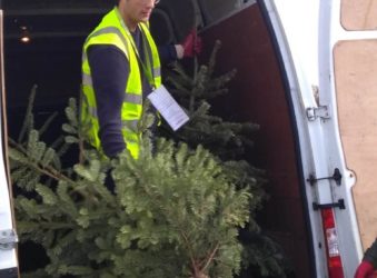 a male offloading a Christmas tree of a van