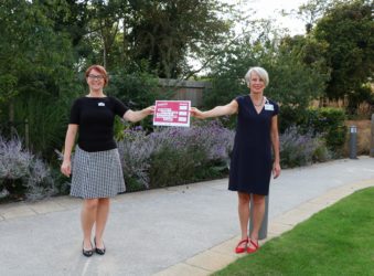HR Director Gemma Manning and CEO Sharon Allen holding a poster which says: 'We pledge to change the way we think and act about mental health at work.'