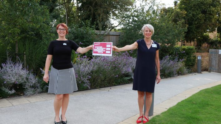 HR Director Gemma Manning and CEO Sharon Allen holding a poster which says: 'We pledge to change the way we think and act about mental health at work.'
