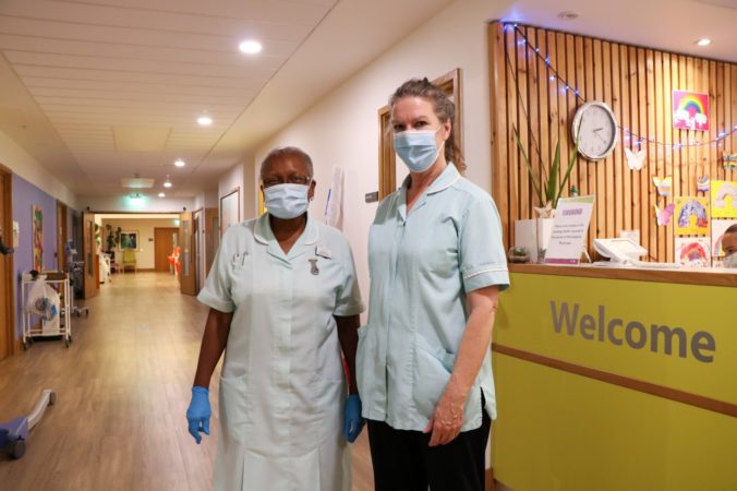 Healthcare assistants wearing masks and gloves, next to Reception desk, Inpatient Unit
