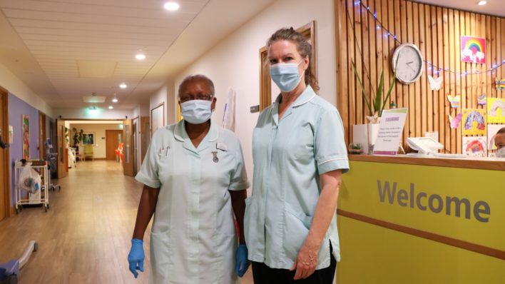 Healthcare assistants wearing masks and gloves, next to Reception desk, Inpatient Unit
