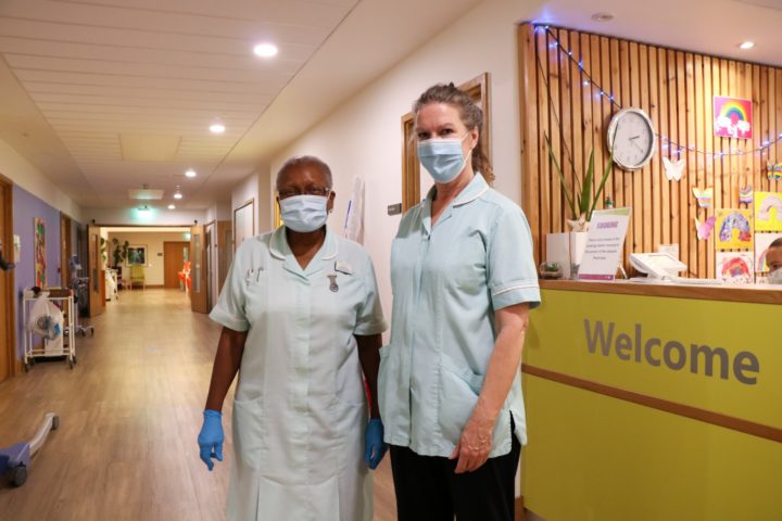 Healthcare assistants wearing masks and gloves, next to Reception desk, Inpatient Unit