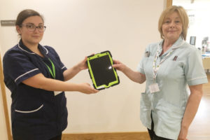 A nurse and a healthcare assistant holding an iPad on the Inpatient Unit