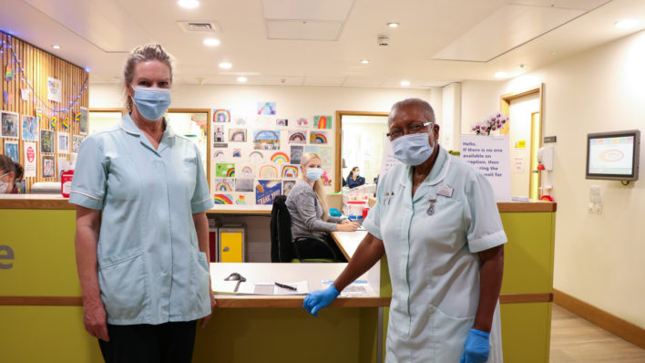 Two of the Hospice's healthcare assistants with one of the ward clerk's on the Inpatient Unit, with rainbow pictures behind