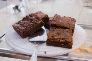 Four mouthwatering chocolate brownies with a cake slice under one, ready to be served