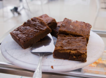 Four mouthwatering chocolate brownies with a cake slice under one, ready to be served