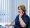 Nurse in dark blue uniform with red trim in office, answering telephone call