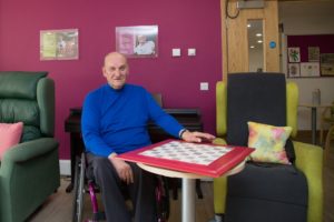 Photo of a patient attending the Hospice’s Living Well weekly social sessions before the pandemic, after an old hobby was reignited and the gentleman made his own chess board. 