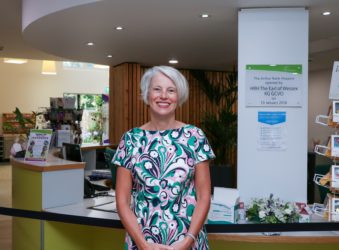 CEO Sharon Allen in a bright summery dress in green, blue, pink and white, smiling at the Hospice's Reception