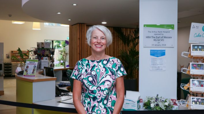 CEO Sharon Allen in a bright summery dress in green, blue, pink and white, smiling at the Hospice's Reception