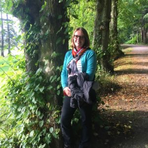 Sally Milligan at the front of a sunlit avenue of trees