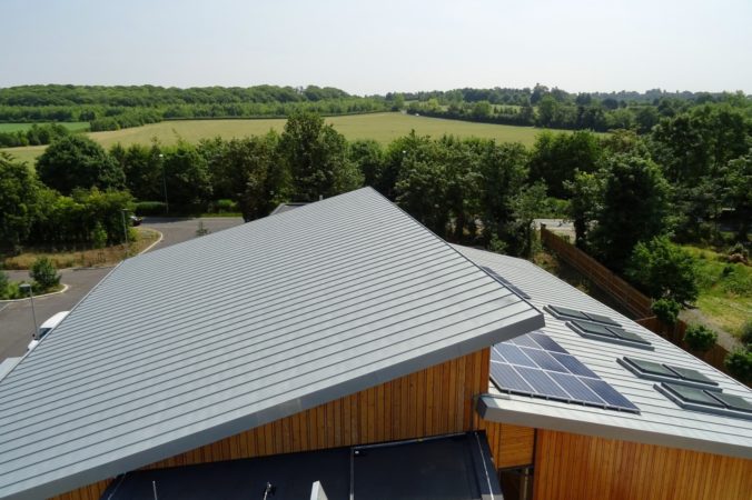 Roof at Arthur Rank Hospice with solar panels and trees and green field in the background
