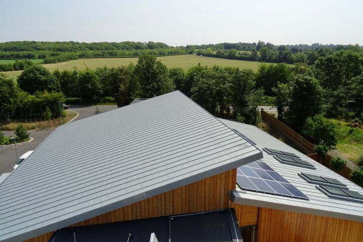 Roof at Arthur Rank Hospice with solar panels and trees and green field in the background