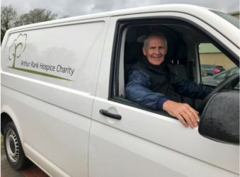Male volunteer smiling in drivers seat of white transit van
